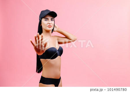 Slim woman in black swimsuit and cap showing a stop gesture with his hand and posing isolated on pink background. People summer vacation rest lifestyle concept Slim woman in black swimsuit and cap showing a stop gesture with his hand and posing isolated on pink background. People summer vacation rest lifestyle concept 101490780