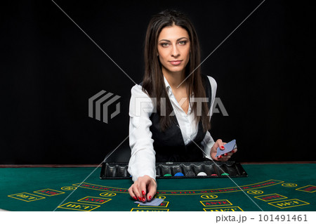 The beautiful girl, dealer, behind a table for poker The beautiful girl, dealer, behind a table for poker 101491461