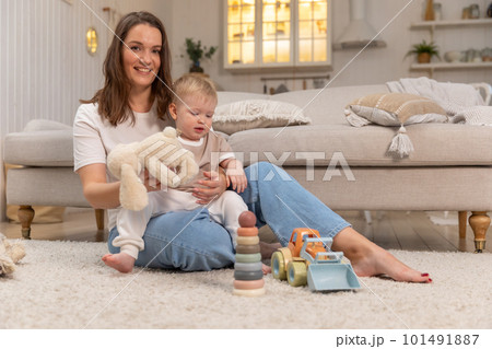 Happy family at home. Mother and baby boy playing with toys at home indoors. Little toddler child and babysitter nanny having fun together. Young woman mom kid son rest in living room 101491887