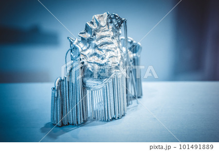 Object printed on metal 3d printer. Dental crowns printed in laser sintering machine. Modern 3D printer printing from metal powder. Concept progressive additive DMLS, SLM, SLS 3d printing technology. Object printed on metal 3d printer. Dental crowns printed in laser sintering machine. Modern 3D printer printing from metal powder. Concept progressive additive DMLS, SLM, SLS 3d printing technology. 101491889