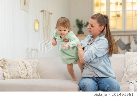 Happy family at home. Mother lifting in air little toddler child daughter. Mom and baby girl playing having fun together at home. Mother hugs baby with love care. Young mother kid rest in living room Happy family at home. Mother lifting in air little toddler child daughter. Mom and baby girl playing having fun together at home. Mother hugs baby with love care. Young mother kid rest in living room 101491961