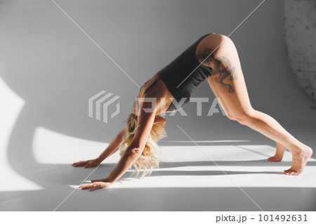 a sexy blonde with tattoos in a leather swimsuit performs sports exercises  101492631