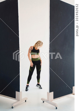 an attractive blonde in a black and green tracksuit poses in the photo studio an attractive blonde in a black and green tracksuit poses in the photo studio 101492632