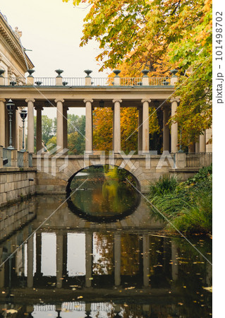 Baths classicist Palace on the Isle in Lazienki Park touristic place in Warsaw. Lazienki Royal Baths Park, Baroque columns Warsaw Poland. Colorful Autumn Foliage and Mirror Reflection on the Lake 101498702