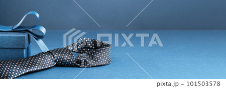 Happy Fathers Day background banner. Two blue gift boxes with ribbon bow and necktie on dark blue table. Monochrome. Gift delivery for him. Male fashion 101503578