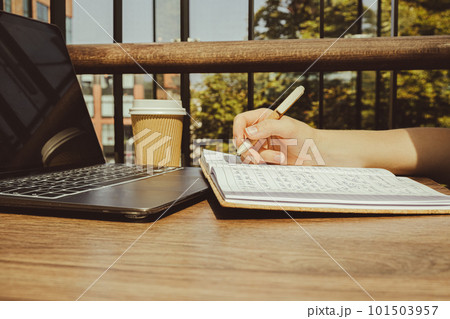 Unrecognizable Young woman study at wooden table in shopping mall food court. Drinking coffee from paper cup. Student making homework Female hands writing on notebook gratitude journal self reflection 101503957