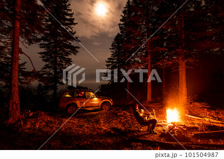 A man sitting at campfire in a tourist camp in a fir forest near the sea. A man sitting at campfire in a tourist camp in a fir forest near the sea. 101504987