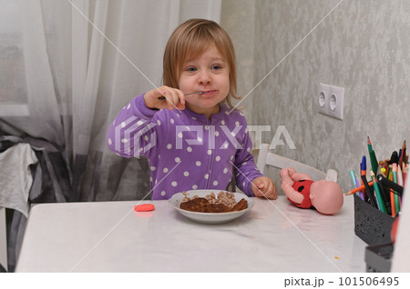a spoon in a little girl's mouth. she eats, and it's very tasty for her. a spoon in a little girl's mouth. she eats, and it's very tasty for her. 101506495