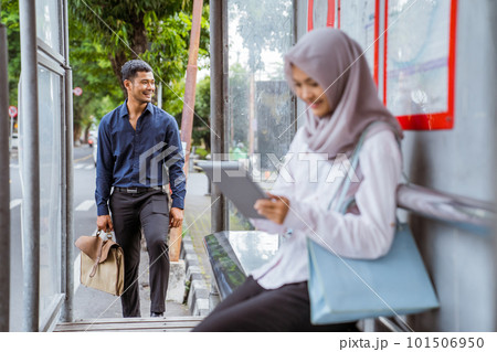 man walking closer as veiled woman sits at bus stop 101506950