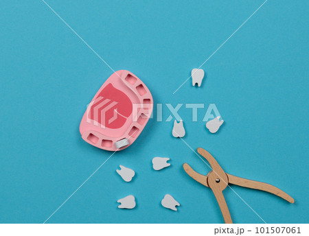 Toy wooden dentist set. Toy jaw with teeth and dentist forceps. Top view on a blue background. Toy wooden dentist set. Toy jaw with teeth and dentist forceps. Top view on a blue background. 101507061
