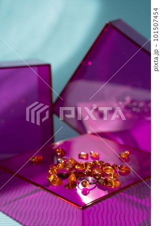 Amber ring and stones on pink glass podium and blue sunlit background. Modern gemstone presentation. November birthstone 101507454