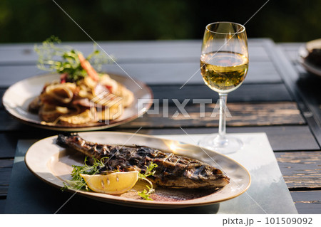 Baked seabass fish in the oven served with slice of lemon baked potatoes and glass of vine. 101509092