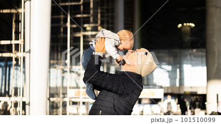Father happily holding and lifting his infant baby boy child in the air after being rejunited in front of airport terminal station. Baby travel concept Father happily holding and lifting his infant baby boy child in the air after being rejunited in front of airport terminal station. Baby travel concept 101510099