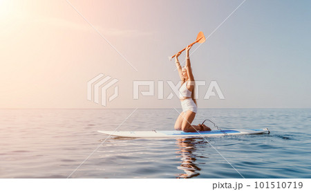 Woman sea sup. Close up portrait of happy young caucasian woman with long hair looking at camera and smiling. Cute woman portrait in bikini posing on sup board in the sea 101510719