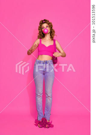 Portrait of beautiful girl woman wearing stylish clothes with bubblegum standing over pink studio background. Girl like sweet lollipop 101513596