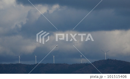 雲が多い夕方の南空と山の稜線に立つ風力発電の風車・春・望遠・空主体・230318pm 101515406