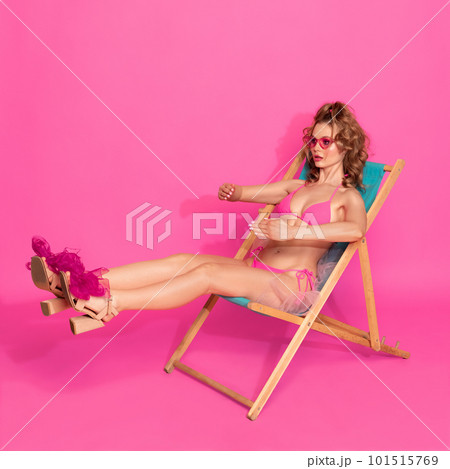 One stunning blond woman, girl wearing swimsuit and sunglasses laying on sunbed over pink studio background. Summer sunbathes 101515769