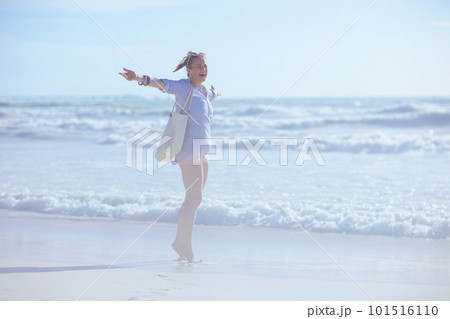 Full length portrait of smiling modern female rejoicing at beach 101516110