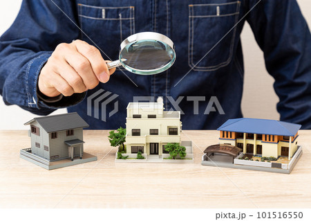 住宅模型を虫眼鏡で観察する男性 101516550