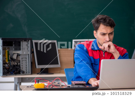 Young male repairman repairing computers in the classroom 101518329