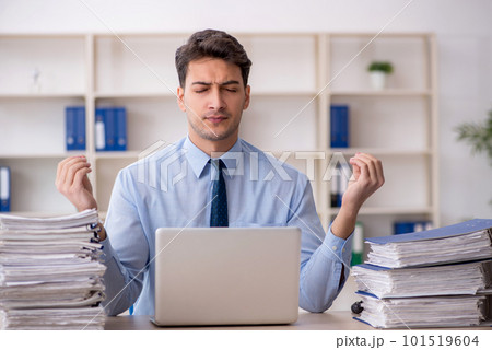 Young male employee and too much work in the office Young male employee and too much work in the office 101519604