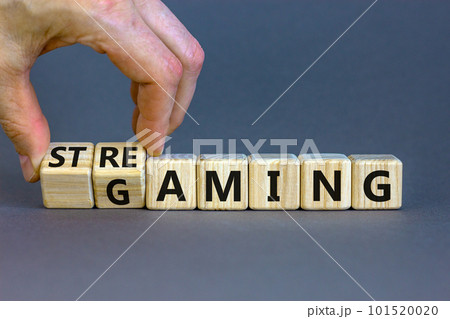 Gaming and streaming symbol. Businessman turns wooden cubes and changes the word gaming to streaming. Beautiful grey table grey background, copy space. Business, gaming and streaming concept. 101520020