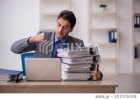 Young male employee and too much work in the office Young male employee and too much work in the office 101520109