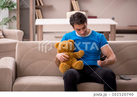 Young man with toy bear at home Young man with toy bear at home 101520740