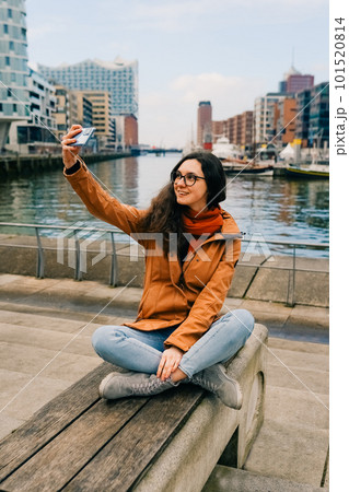 Happy woman taking selfie through smart phone in Hafencity, Hamburg, Germany Happy woman taking selfie through smart phone in Hafencity, Hamburg, Germany 101520814