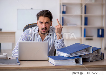 Young male employee and too much work in the office 101522300