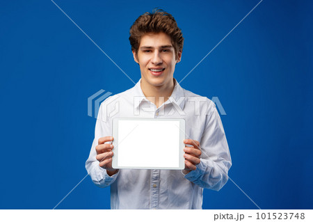 Happy young man showing digital tablet isolated on blue background. 101523748
