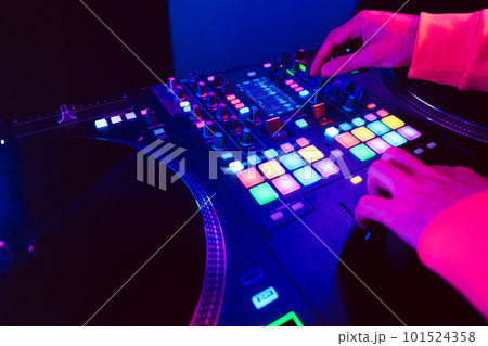 Hands of a DJ creating and regulating music on dj console mixer at club concert 101524358
