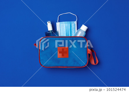 First aid kit with mask and sanitizer on blue background 101524474