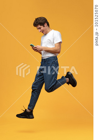 Young happy man using his phone against yellow background. Young happy man using his phone against yellow background. 101525070