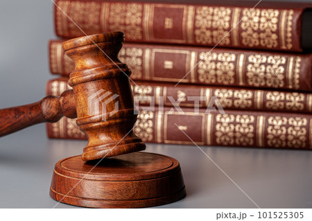 Brown wooden gavel with stack of books on gray table Brown wooden gavel with stack of books on gray table 101525305