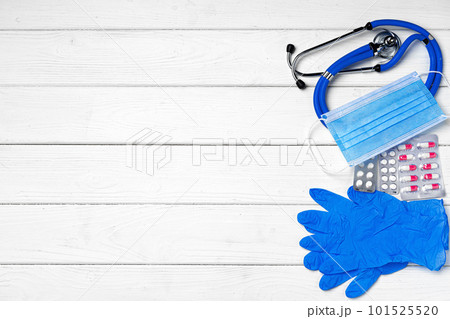 Medical equipment. Stethoscope, mask and pills on wooden desk close up 101525520