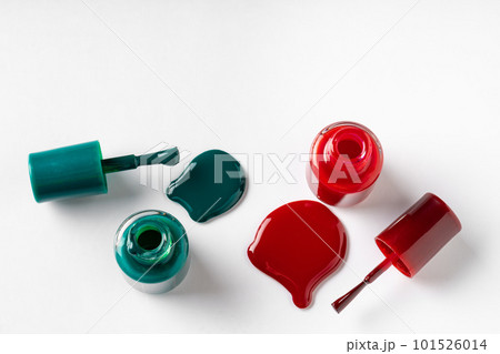 Nail polishes spilled out of bottles on white background 101526014