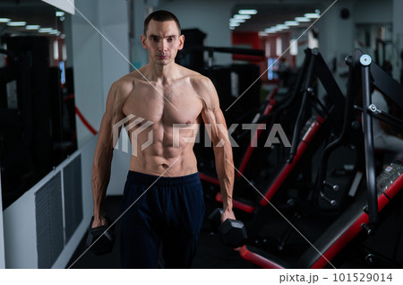 Shirtless man doing bicep exercises with dumbbells in the gym. Shirtless man doing bicep exercises with dumbbells in the gym. 101529014
