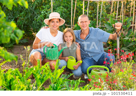 Happy family with watering cans in their hands in vegetable garden 101530411