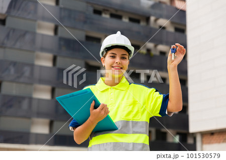 Young woman on building site showing key Young woman on building site showing key 101530579