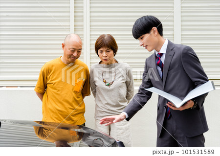 レンタカー屋やシェアカーで営業マンから傷のチェックをし説明を受ける50代〜60代のシニアの夫婦 レンタカー屋やシェアカーで営業マンから傷のチェックをし説明を受ける50代〜60代のシニアの夫婦 101531589