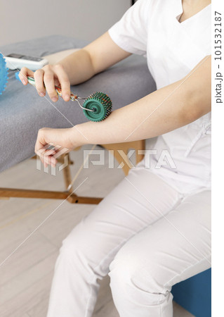 Closeup Rehabilitation Specialist, Physical Therapist Shows Rehab Tool Meso Roller With Titanium Needles On Hand, Massage Ball With Pimples in Therapeutic Room. Healthcare, Rehabilitation. Vertical 101532187