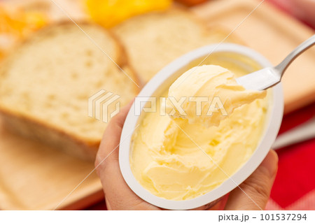 パンにバターを塗るシニア女性の手元 101537294