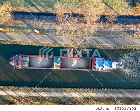 Aerial view from a drone of a cargo canal ship passes by over the canal on a sunny winter day 101537802