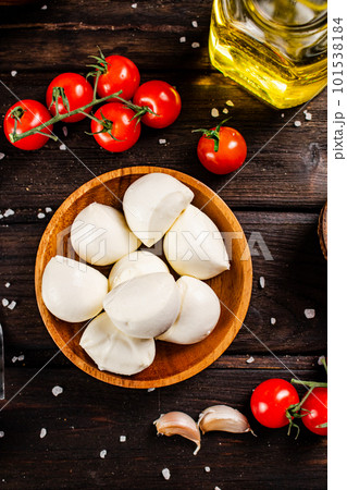 Mozzarella cheese on a plate on a table with tomatoes and spices. Mozzarella cheese on a plate on a table with tomatoes and spices. 101538184