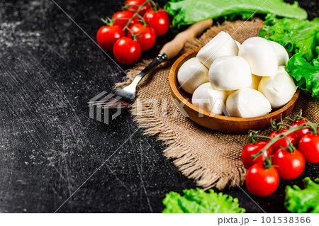 Mozzareella in a plate on a napkin with tomatoes and lettuce. Mozzareella in a plate on a napkin with tomatoes and lettuce. 101538366