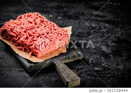 A piece of raw minced meat on a cutting board. A piece of raw minced meat on a cutting board. 101538444
