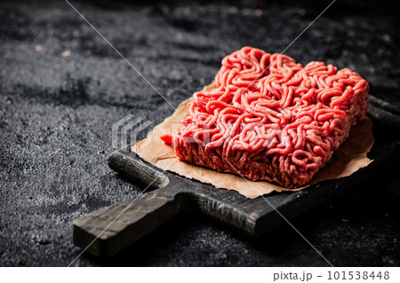 A piece of raw minced meat on a cutting board. A piece of raw minced meat on a cutting board. 101538448