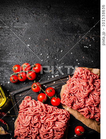 Raw minced meat on a cutting board with cherry tomatoes. Raw minced meat on a cutting board with cherry tomatoes. 101538636