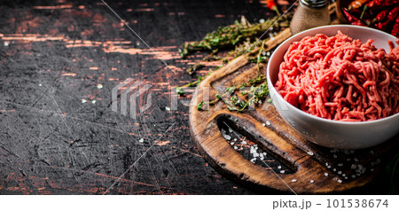 Minced meat in a bowl on a cutting board with sprigs of thyme. Minced meat in a bowl on a cutting board with sprigs of thyme. 101538674